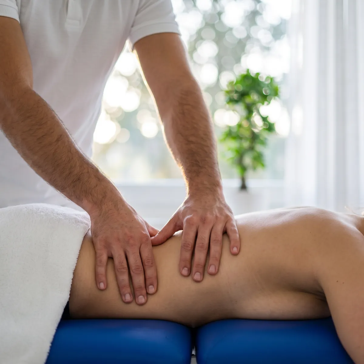 Hände bei der Massage des unteren Rückens
