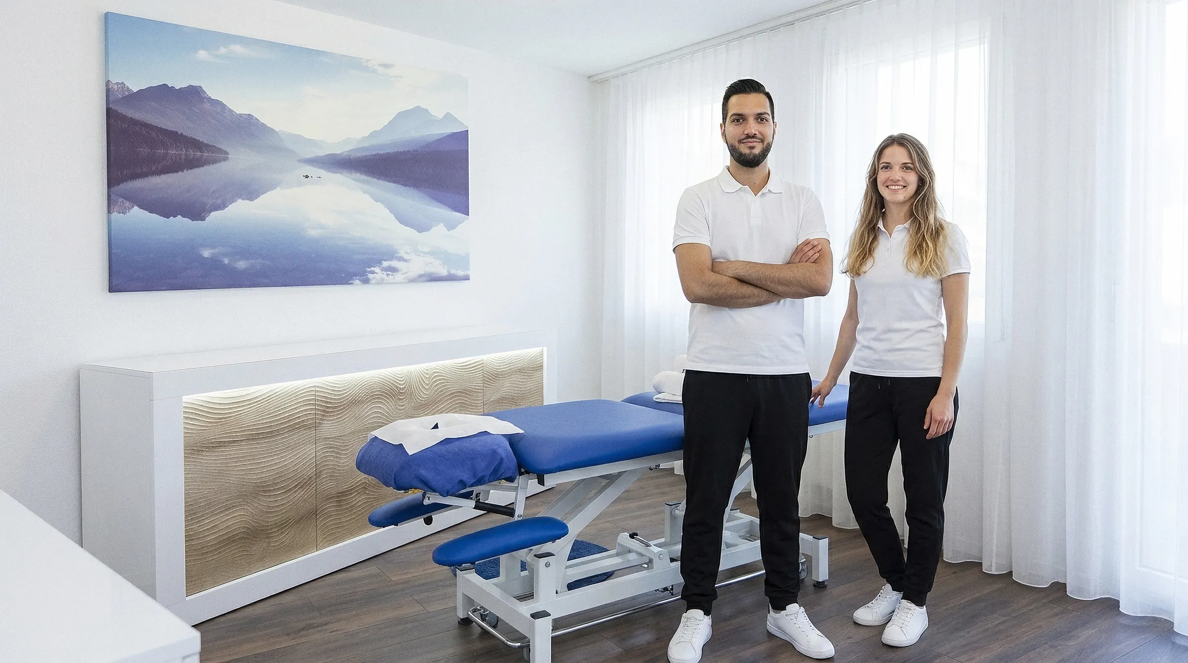 Murat Aydin und Dominique Wüthrich in weissen Poloshirts stehen neben der Behandlungsliege im Behandlungsraum der MassagePraxis Aydin in Cham